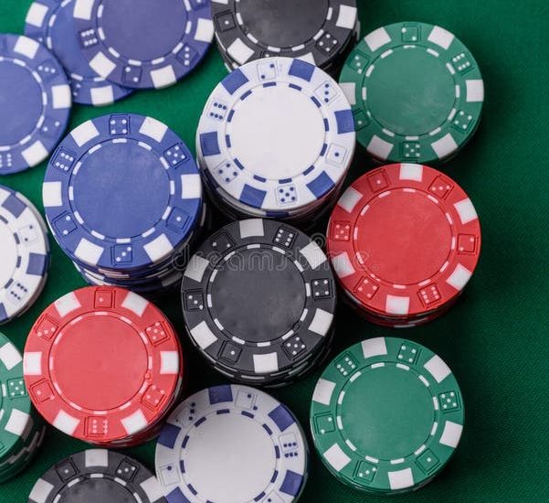 A close-up view of various poker chips stacked on a green table, emphasizing gambling elements associated with baccarat.