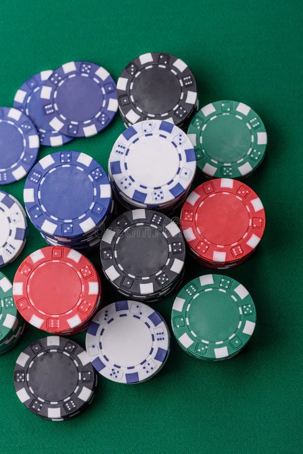 A close-up view of various poker chips stacked on a green table, emphasizing gambling elements associated with baccarat.