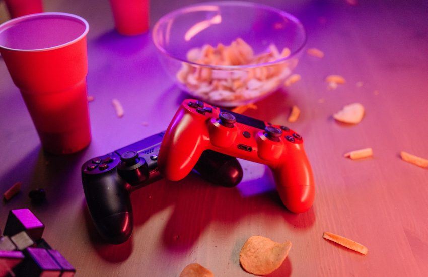 A dynamic gaming setup featuring red and black game controllers, snacks, and vivid lighting. — Betting Sites Ireland Offers S